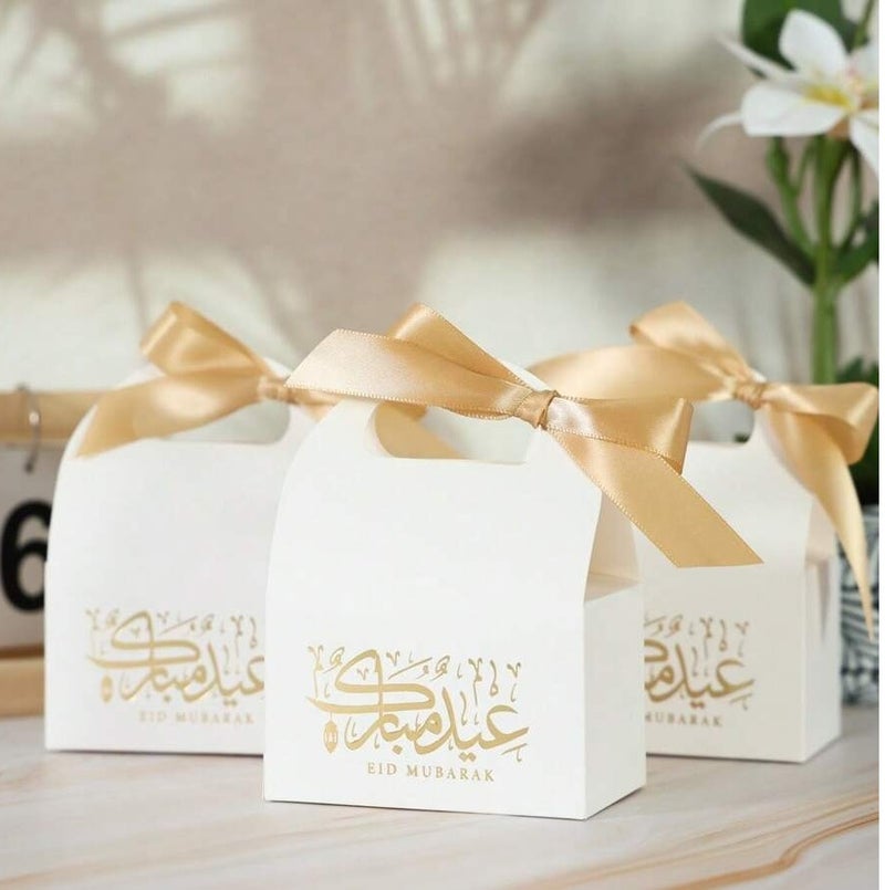 توزيعات العيد 10  علب هدايا بيضاء مزخرفة بعبارة عيد مبارك مع شريطة ذهبية، مناسبة لتقديم الحلوى وزينة الحفلات والمناسبات - Image 2